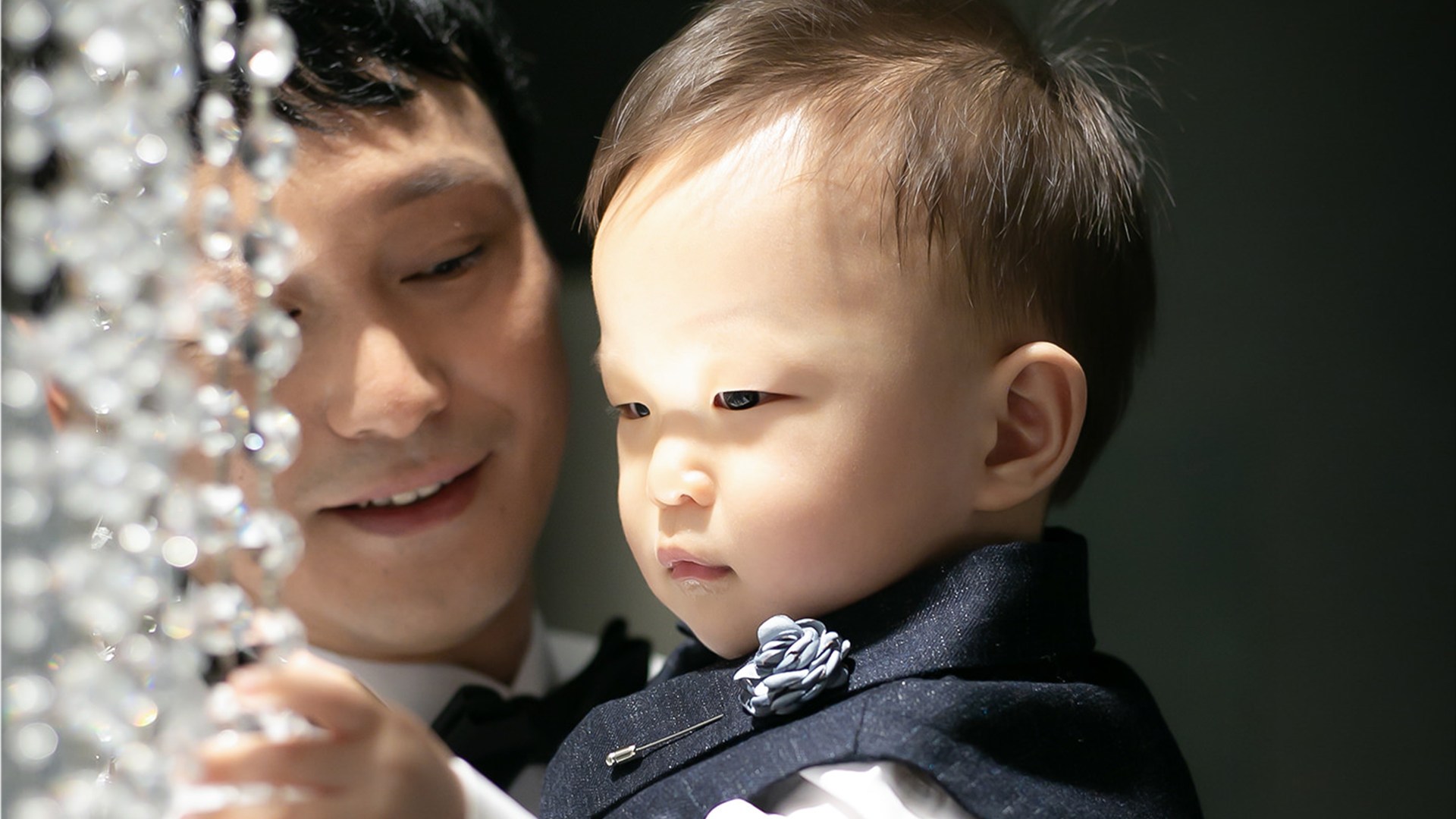 아빠 품에서 크리스털 장식을 보는 아기